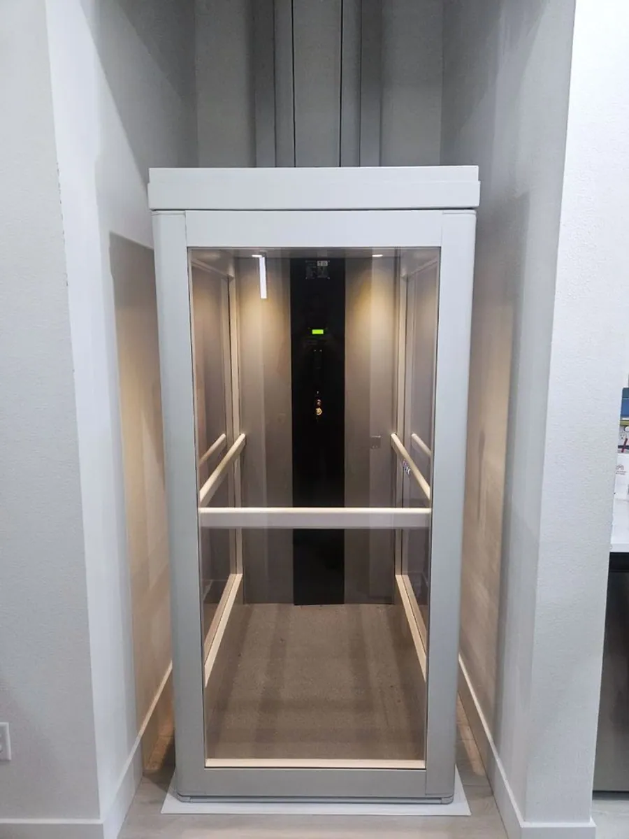 Panoramic glass elevator cabin interior with stainless control panel